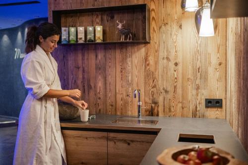 a woman standing in a kitchen preparing food at Hotel Laurin in Dobbiaco