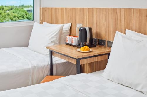 a room with two beds and a table with a tv at Go Hotels Plus Bacolod - Newly Renovated in Bacolod