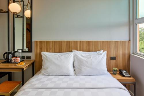 a bedroom with a bed with white pillows and a desk at Go Hotels Plus Bacolod - Newly Renovated in Bacolod