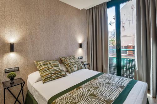 ein Schlafzimmer mit einem Bett und einem großen Fenster in der Unterkunft Apartamentos Suites Oficentro Original in Málaga