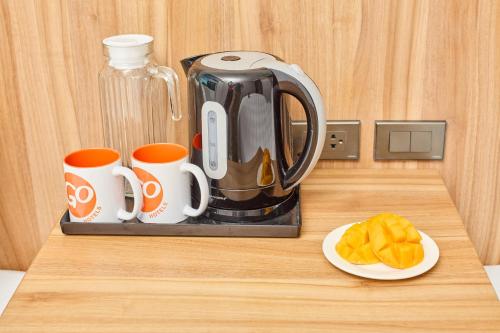 a coffee maker and two cups and a plate of food at Go Hotels Plus Bacolod - Newly Renovated in Bacolod