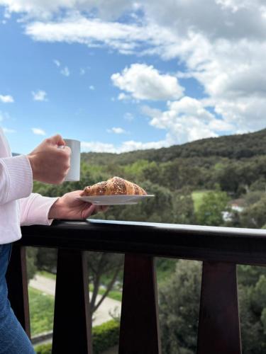 a person holding a plate with a piece of cake on a balcony at Apartamentos Cal Ratero in Maçanet de Cabrenys