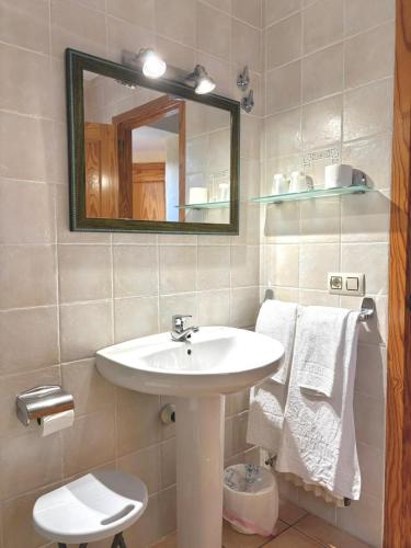 a bathroom with a sink and a mirror and towels at Apartamentos Cal Ratero in Maçanet de Cabrenys