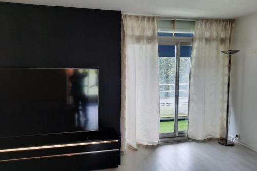 - un salon avec une télévision à écran plat à côté d'une fenêtre dans l'établissement Joli 86m avec terrasse proche de la plage !, à Arcachon