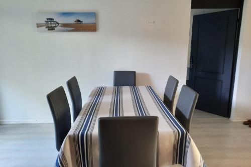 une table de salle à manger avec des chaises et un tableau au mur dans l'établissement Joli 86m avec terrasse proche de la plage !, à Arcachon