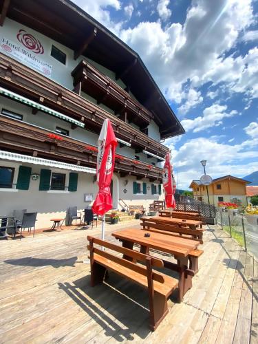 a group of wooden benches in front of a building at Hotel Wildrose in Neukirchen am Großvenediger