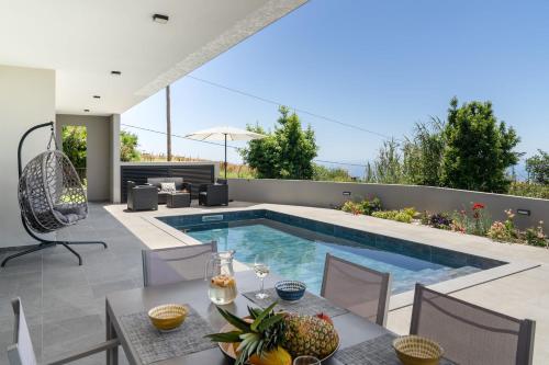 a swimming pool in a backyard with a table and chairs at Vila da Ponta do Pargo by An Island Apart in Ponta do Pargo