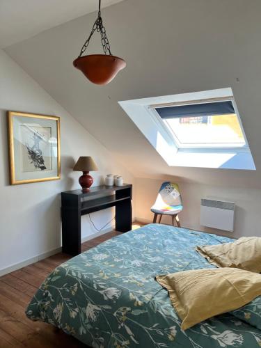 - une chambre avec un lit, un bureau et une lucarne dans l'établissement Duplex terrasse, à Fréhel