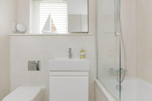 a white bathroom with a sink and a shower at St Marks Cottage in Swanage
