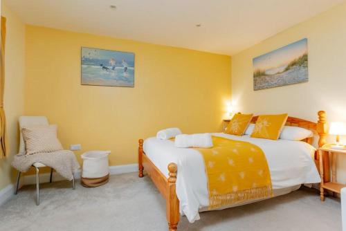a yellow bedroom with two beds and a chair at St Marks Cottage in Swanage
