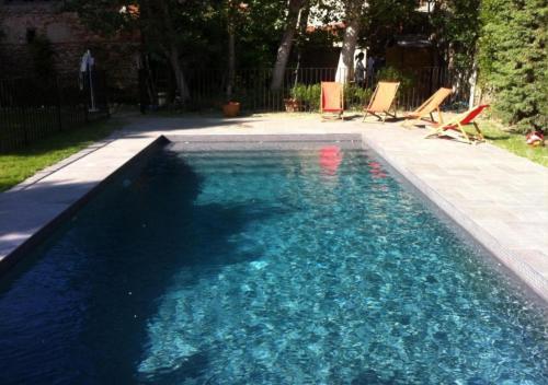 une piscine avec quelques chaises dans une cour dans l'établissement Maison Traditionnelle Catalane avec terrain de tennis et piscine, à Palau-del-Vidre