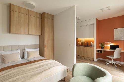 a bedroom with a bed and a chair and a desk at Trevi Apartments Katowice - City Center - Spodek MCK NOSPR in Katowice