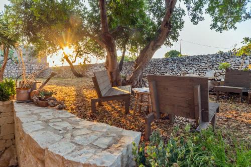 Un banco y una mesa en un patio con un muro de piedra. en A Casa Ruah - IsulaTravel, en Scuola