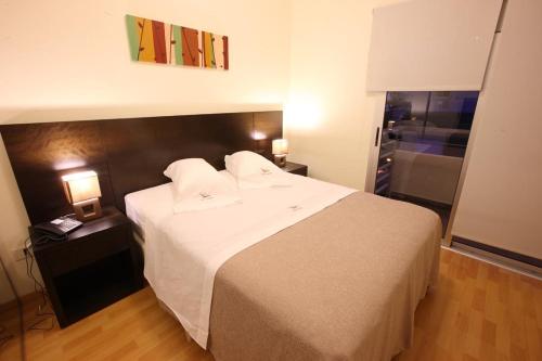 a bedroom with a large white bed with two lamps at Lecer Apart in Buenos Aires