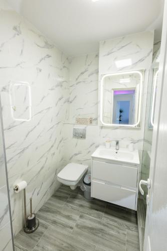 a white bathroom with a sink and a toilet at Apartament Lucas Sighișoara in Sighişoara