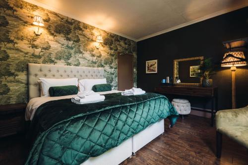 a bedroom with a bed with a green comforter at Gaskell Arms in Much Wenlock