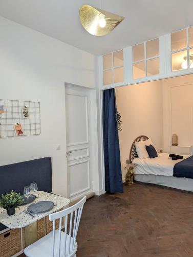 a living room with a bed and a table and a dining room at Barbieux Charmant studio au pied du métro in Roubaix