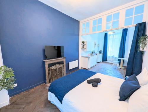 a blue bedroom with a large bed and a television at Barbieux Charmant studio au pied du métro in Roubaix