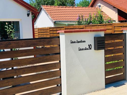 a wooden fence with a gate with a sign on it at Dévér Apartman in Gárdony