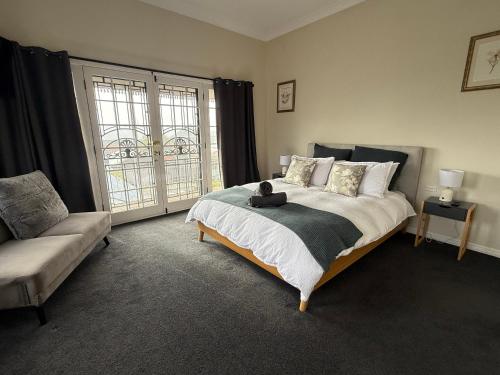 a bedroom with a bed and a couch and a window at Historical home is a cosy stay located in central Bathurst in Bathurst