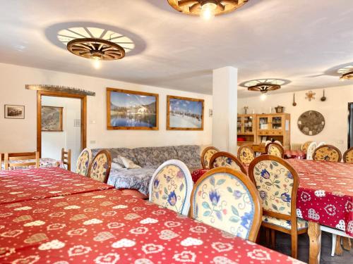 a dining room with tables and chairs and a couch at Chalet Rustico Bertolini per Gruppi! in Vermiglio