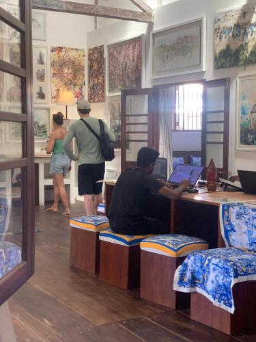 a man sitting at a desk with a laptop in a room at ArtNEST Gallery Stay , Pedlars St , Galle Fort in Galle