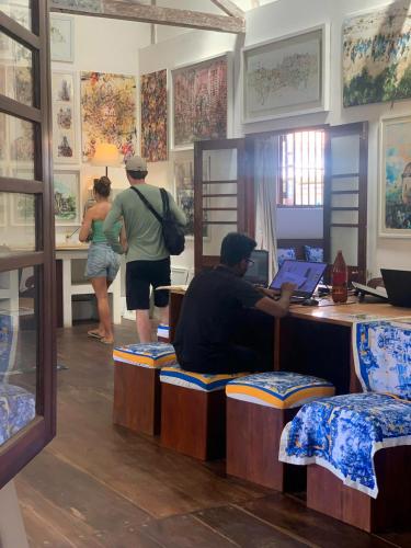 a man sitting at a desk with a laptop at ArtNEST Gallery Stay , Pedlars St , Galle Fort in Galle