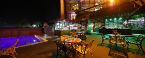 a patio with tables and chairs and a pool at night at The Cox Today Limited in Cox's Bazar