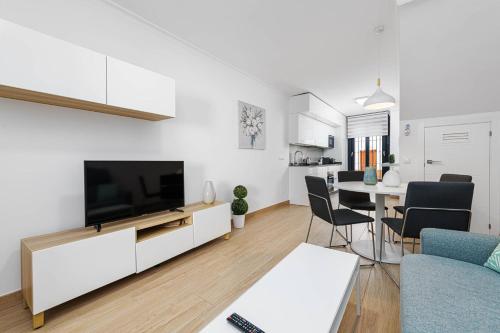 a living room with a television and a dining room at Nueva 22 Suites in Nerja by Solaga Holiday Homes in Nerja