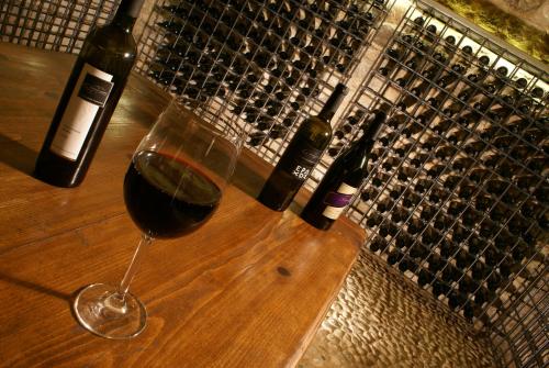 a glass of wine sitting on a table with wine bottles at Argyriou Wine Tasting Guest House in Polydrossos
