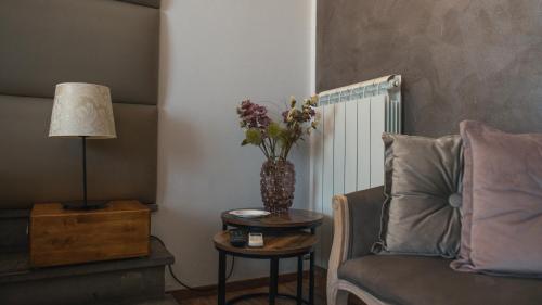 a living room with a vase of flowers on a table and a chair at B&B 7 Rooms in Pisa