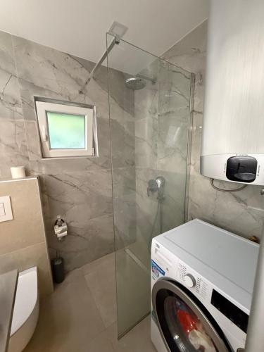 a washing machine in a bathroom with a shower at Golden Wave Apartment in Vir