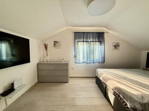 a bedroom with a bed and a tv and a window at Golden Wave Apartment in Vir