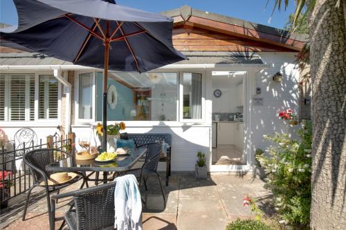 a patio with a table and an umbrella at Lucy Lou, charming holiday bungalow in Devon in Galmpton-on-the-Dart