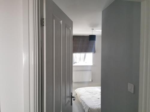 Eine weiße Tür führt zu einem Schlafzimmer mit einem Bett. in der Unterkunft The Grange Cute Modern Stay in Gerrards Cross