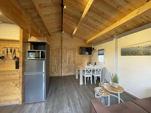 a kitchen and dining room of a cabin with a refrigerator at Gezellig Chalet kindvriendelijk park VP030 in Heinkensand