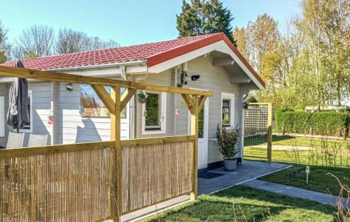 a small white house with a wooden fence at Gezellig Chalet kindvriendelijk park VP030 in Heinkensand