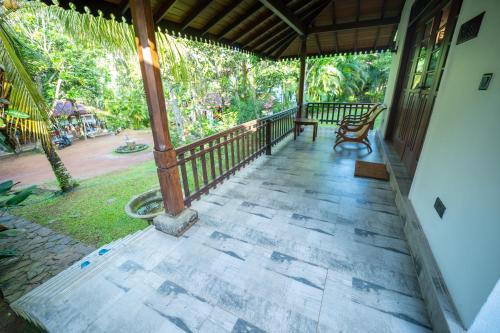a porch of a house with two chairs on it at Araliya Gardens Hotel in Hikkaduwa