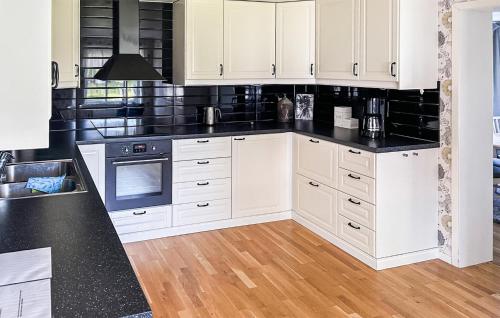 a kitchen with white cabinets and black counter tops at Cozy Home In Dörarp With Sauna in Dörarp