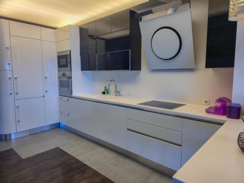 a kitchen with white cabinets and a sink and a mirror at Apartment Iva in Omiš