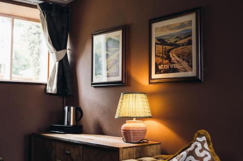 a lamp on a table next to a wall with pictures at Gaskell Arms in Much Wenlock