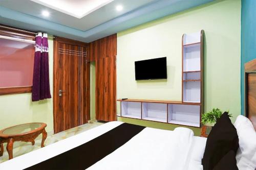 a bedroom with a bed and a tv on a wall at Upper Tapovan Resort in Rishīkesh