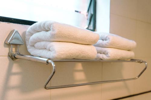 a stack of towels on a towel rack in a bathroom at Bisque Magaji Orchid - Malleshwaram, Near Mantri Square Mall & Majestic in Bangalore