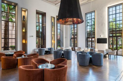 a restaurant with tables and chairs and a chandelier at Pickalbatros Hôtel Du Golf - Adults Friendly 16 Years Plus- All-Inclusive in Marrakech