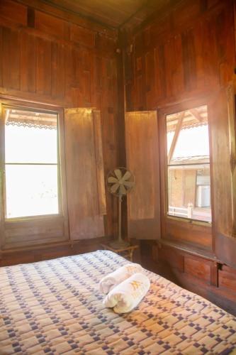 a bedroom with a bed and two windows at Teak House Homestay II in Ban Thung Satong