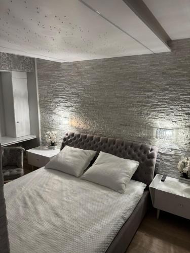 a bedroom with a large bed and a brick wall at AKOYA APARTMENT Cristal Bianco in Koszalin