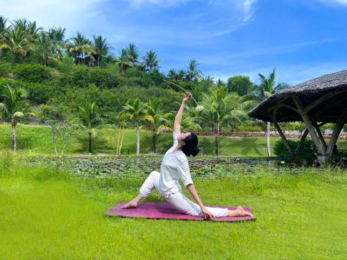 a woman sitting on a blanket in the grass at Fusion Resort Cam Ranh - All Spa Inclusive in Cam Ranh