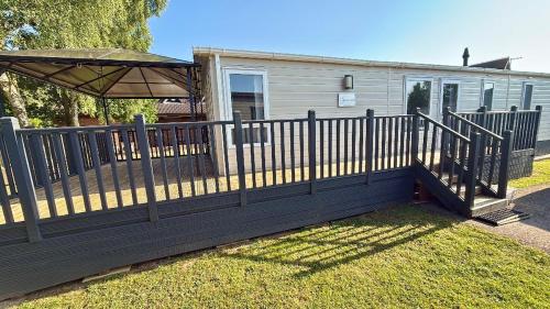 a wooden fence with an umbrella in front of a house at Golfing & Family Breaks in Luxury Lodge in Tydd Saint Giles