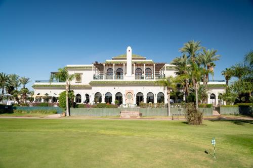 a large white house with palm trees in front of it at Pickalbatros Hôtel Du Golf - Adults Friendly 16 Years Plus- All-Inclusive in Marrakech
