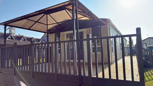 a wooden deck with an umbrella on a house at Golfing & Family Breaks in Luxury Lodge in Tydd Saint Giles